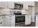 Stainless steel oven and range with white cabinets and backsplash at 5128 Noble Village Way # 35, Lilburn, GA 30047