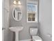 Cozy bathroom with an oval mirror, pedestal sink, toilet, and natural light at 1530 Wehunt Se Cir # 19, Smyrna, GA 30082
