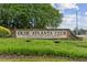 A stone sign for Olde Atlanta Club, an Arthur Hills Golf Course Community, surrounded by lush greenery at 7020 Grand View Way, Suwanee, GA 30024
