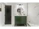 This updated bathroom has a green vanity, marble tile, black fixtures, a round mirror, and a glass-walled shower at 2019 Emerald Dr, Jonesboro, GA 30236
