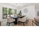 Bright dining room with modern chandelier, black table and four cream upholstered chairs overlooking a window with a wooded view at 2019 Emerald Dr, Jonesboro, GA 30236
