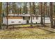 Charming home exterior with white stucco, dark roof, and natural wood shutters nestled in a wooded area at 2019 Emerald Dr, Jonesboro, GA 30236
