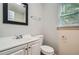 Bathroom with a framed mirror, white cabinets and sink, toilet and a window at 7112 Greenway Sw Cv, Covington, GA 30014