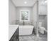 Well-lit bathroom featuring a modern standalone tub, marble wall tiles, and tile flooring at 1528 Alder Sw Ln, Atlanta, GA 30311