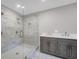 Modern bathroom featuring a glass shower, gray cabinets with dual sinks, and marble-style wall tiles at 1528 Alder Sw Ln, Atlanta, GA 30311