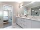 Bathroom featuring dual sinks, white cabinets, and a large mirror with a view of a spacious shower at 175 Stovall Se St, Atlanta, GA 30316