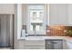A well-lit kitchen featuring brick backsplash, white cabinets, stainless steel appliances and a farmhouse sink at 175 Stovall Se St, Atlanta, GA 30316