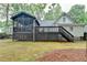 View of the back exterior featuring an elevated deck, screened porch, and lush green lawn at 2130 Monticello Pl, Lawrenceville, GA 30043