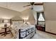 Cozy bedroom with black bed frame, dark wood accents, sloped ceiling, and a window with grey drapes at 2130 Monticello Pl, Lawrenceville, GA 30043