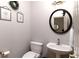 Powder room with pedestal sink, round mirror, and decorative wall art at 630 Bluff Oak Ct, Roswell, GA 30076