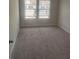 Bright bedroom featuring neutral paint, plush carpet, and large windows with pleasant neighborhood views at 6424 Rosetta Dr, South Fulton, GA 30331
