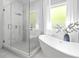Bright bathroom with a sleek glass shower, soaking tub, and marble tile at 1188 Woodtrace Ln, Auburn, GA 30011