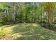 Landscaped backyard with a lush lawn, a mulch flower bed, and shade trees at 1315 Badingham Dr, Cumming, GA 30041