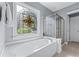 Bright bathroom featuring a soaking tub with a stained glass window and a glass enclosed shower at 1315 Badingham Dr, Cumming, GA 30041