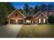 Charming brick home with two-car garage, manicured lawn, and a well-lit driveway at twilight at 1315 Badingham Dr, Cumming, GA 30041