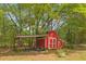 Exterior of a red outbuilding for storage on a treed lot at 928 Rocky Creek Rd, Hampton, GA 30228