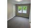 A simple bedroom featuring carpeted floors, a double-paned window and a door to the exterior hallway at 169 Long Dr, Marietta, GA 30060