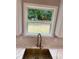 Close-up of a stylish kitchen sink with a gold faucet and marble backsplash beneath a bright window at 169 Long Dr, Marietta, GA 30060