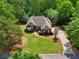 Charming home featuring a manicured lawn, brick accents, and a long, winding driveway, all surrounded by lush greenery and mature trees at 5030 Princeton Trce, Cumming, GA 30041