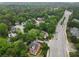 Expansive aerial view of a neighborhood with tree-lined streets, showcasing a brick home and surrounding green spaces near a main road at 100 Barnard Pl, Atlanta, GA 30328