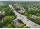 Wide aerial view of property showcasing brick house, surrounding neighborhood, mature trees, and a nearby thoroughfare at 100 Barnard Pl, Atlanta, GA 30328