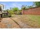 Lush backyard featuring gravel, landscaping, and manicured lawn, all enclosed by a classic brick wall at 100 Barnard Pl, Atlanta, GA 30328