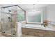 Bathroom featuring a glass-enclosed shower, soaking tub, and travertine tile at 100 Barnard Pl, Atlanta, GA 30328