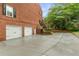 A large driveway leading to a two-car garage and side entrance of a distinguished brick home with manicured landscaping at 100 Barnard Pl, Atlanta, GA 30328