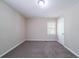 A vacant bedroom with a window, beige walls, and plush carpeting at 1774 Austin Dr, Decatur, GA 30032