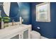 Charming half bathroom with a round mirror, white vanity, and bright blue painted walls at 4909 Glenwhite Dr, Duluth, GA 30096