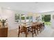 Elegant dining room with a long wooden table, stylish chairs, and large windows offering views of the backyard at 4909 Glenwhite Dr, Duluth, GA 30096