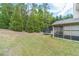 Large backyard with green lawn, surrounding trees, screened-in porch, and a trampoline at 882 Nestling Dr, Lawrenceville, GA 30045