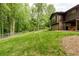 Backyard with mature trees adjacent to a brown house with brick foundation at 2425 Maclaren Cir, Dunwoody, GA 30360