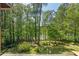 A serene backyard view showcases the lush, wooded landscape with a glimpse of the tranquil lake at 5159 Sw East Shore Sw Dr, Conyers, GA 30094