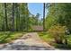 Long, paved driveway leading to a charming home surrounded by lush greenery and mature trees on a sunny day at 5159 Sw East Shore Sw Dr, Conyers, GA 30094