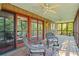 The screened porch has a ceiling fan, wood flooring, and comfortable wicker furniture at 5159 Sw East Shore Sw Dr, Conyers, GA 30094