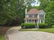 Charming two-story home boasts a red front door and lush landscaping, nestled among mature trees at 1511 Harbor Watch Ct, Woodstock, GA 30189