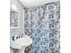 Updated bathroom with a pedestal sink and a floral-patterned shower curtain at 1563 Greenwood Dr, Norcross, GA 30093