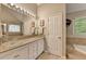 Well-lit main bathroom with double sinks, glass vessel bowls, and a separate soaking tub at 5574 Wynhall Dr, Peachtree Corners, GA 30071