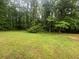 Lush green backyard featuring mature trees, well-maintained grass, and natural surroundings at 5769 Shadow Creek Dr, Lithonia, GA 30058
