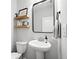 Well-lit half bathroom with a pedestal sink, decorative mirror, and floating shelves for storage and display at 461 Timberleaf Rd, Canton, GA 30115