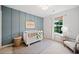 Stylish Bedroom with a blue accent wall, a white crib, a window, and a chair at 461 Timberleaf Rd, Canton, GA 30115