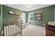 Charming Bedroom with sage walls, vintage metal crib, window with backyard view, and hardwood bookshelf at 461 Timberleaf Rd, Canton, GA 30115
