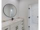 Modern bathroom with marble countertops, a sleek round mirror, and a doorway to the hallway at 51 Deer Canyon Dr, Auburn, GA 30011