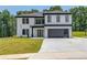 Modern two-story home with a black garage door, black window trim, and a well-manicured lawn at 51 Deer Canyon Dr, Auburn, GA 30011