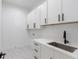 Convenient laundry room with ample cabinet space, quartz countertop, stainless sink, and stylish tile flooring at 51 Deer Canyon Dr, Auburn, GA 30011