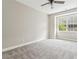 Bedroom featuring neutral paint, plush carpet, ceiling fan, and large window with views of the landscaped property at 565 Stone Field Nw Run, Marietta, GA 30060