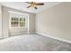 Spacious bedroom featuring neutral paint, plush carpet, ceiling fan, and large window with views of the landscaped property at 565 Stone Field Nw Run, Marietta, GA 30060