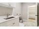 Bright laundry room featuring white cabinets, quartz countertops, stainless steel sink, and a connected shelved storage room at 565 Stone Field Nw Run, Marietta, GA 30060