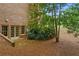 Brick home featuring a door to the backyard and landscaped with pine straw and lush foliage at 1100 Kensington Ct, Johns Creek, GA 30022